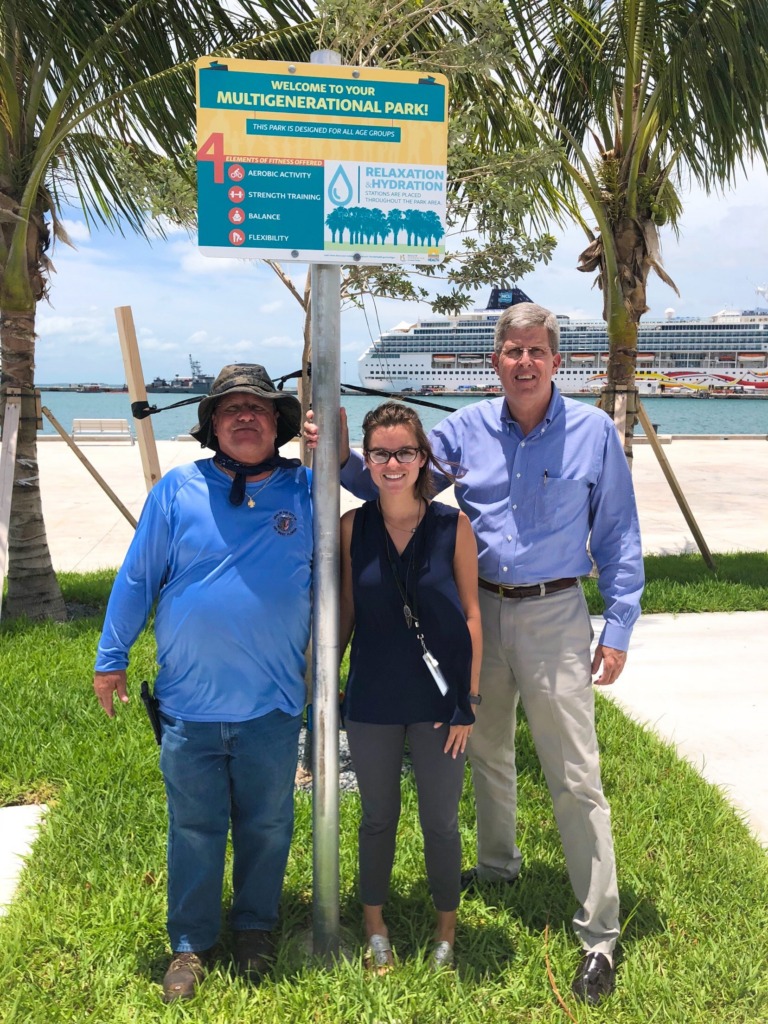 Three people pose with a multigenerational sign.