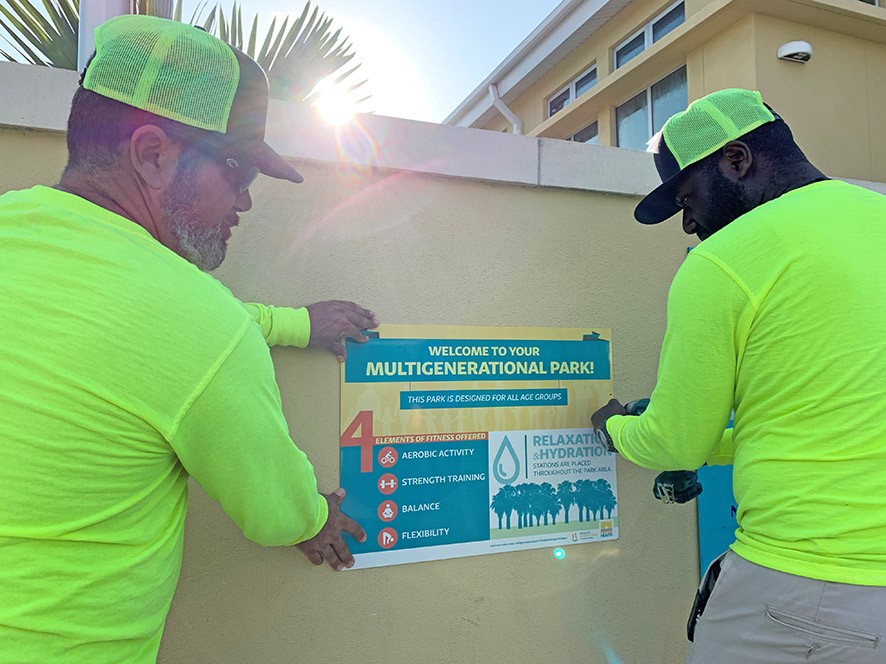 Two people install multigenerational park sign.